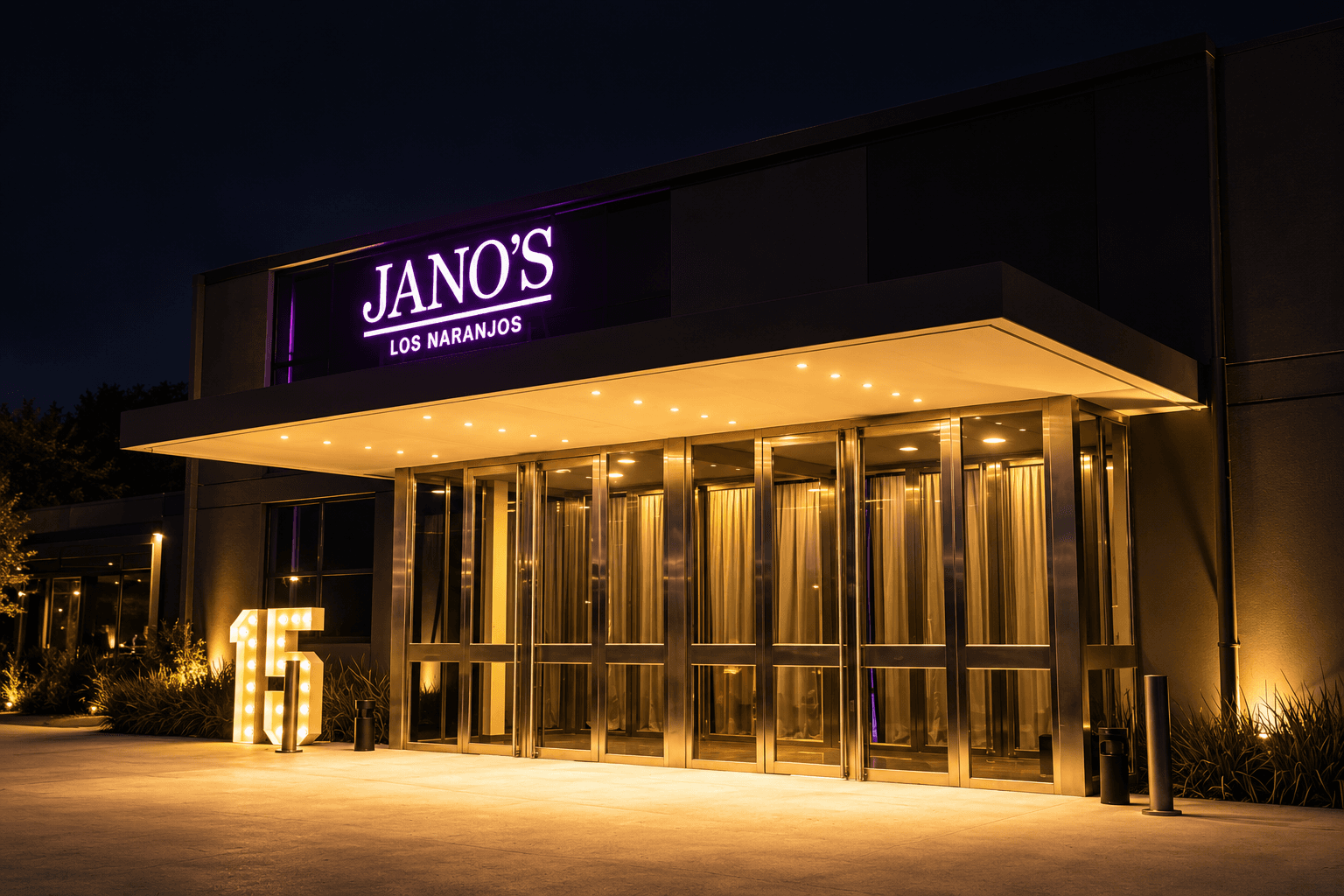 Entrada iluminada del salón Jano's Los Naranjos de noche